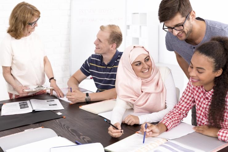 Praxissituation Jobcenter Anleiterin erklärt einem Studierenden etwas und Studierende arbeiten gemeinsam an einer Aufgabe